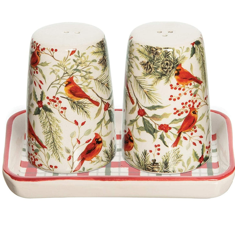 Salt and pepper shakers on a tray.  The shakers are off white background with red cardinals and woodland greenery. They sit on a try that is red & green plaid on off white.