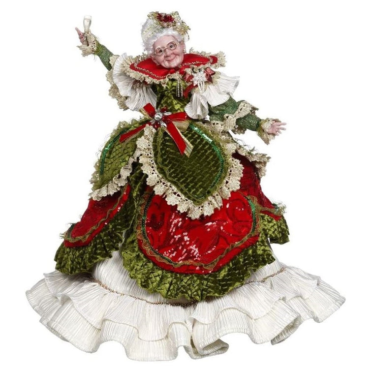 Mrs. Claus figurine in a red and green velvet dress with cream color ruffled under skirt. She's holding a champagne glass.