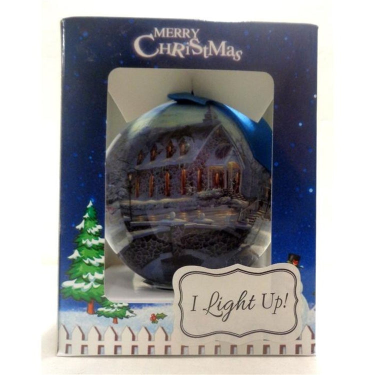 Round ball ornament sits inside open front box. Box has text "Merry Christmas" “I light up” Ball shows stone front church.