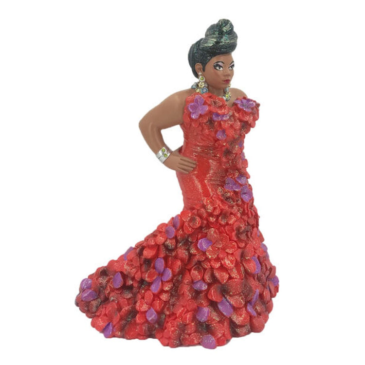 Drag queen figurine with black hair up. Wearing red with purple accents floor length dress. Has gold bracelets and hands on hips.