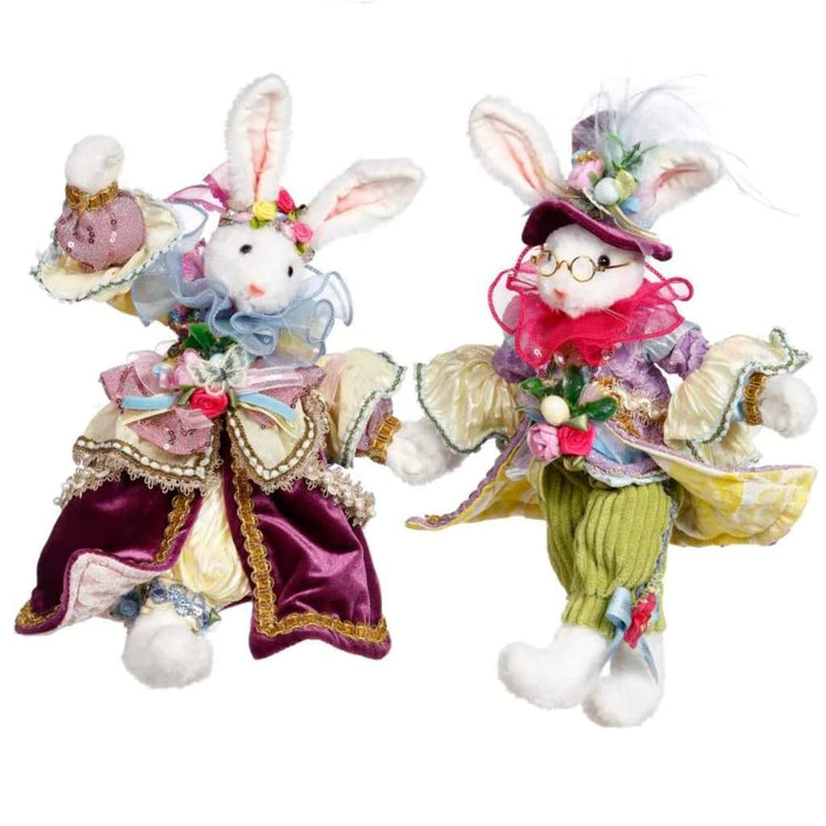 2 rabbit figures festivley dressed for Easter with purple and green frilly clothes.  He wears a top hat with his ears sticking through.  Lots of embellishments.