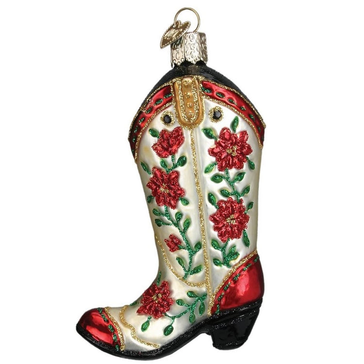 Blown glass ornament of a cream color cowgirl boot with red and black accent at the toe and heel, along with red poinsettia pattern on the actual boot.