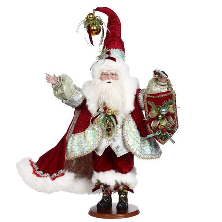 Santa wearing a red cloak, matching suit and hat all lined in white fur, holding a pennant with ornaments and bells.