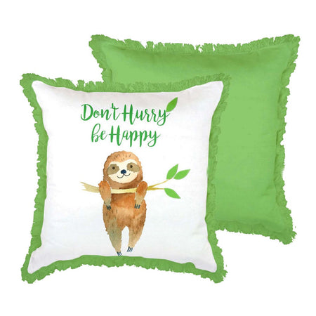 White pillow with green fringe. Text "Don't Hurry be Happy. below text a smiling sloth is hanging from a tree branch