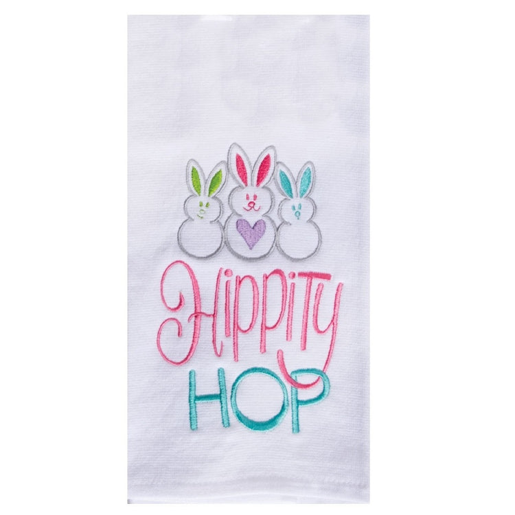 White towel with 3 small embroidered bunnies with different color ears, the words "hippity hop" are also embroidered in pink and like blue.
