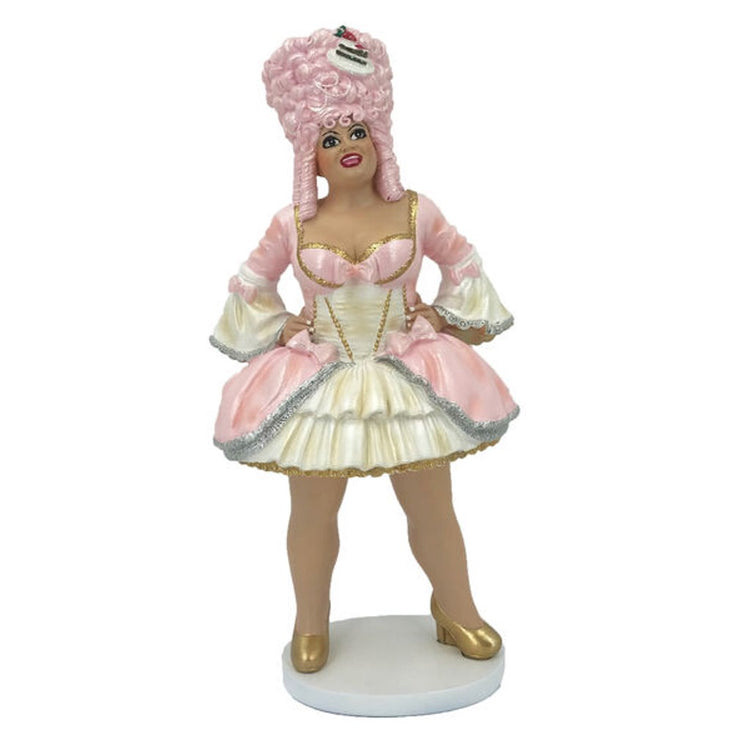 Drag queen figurine with tall pink wig, wearing pink and yellow dress. Standing with hands on hips. Wearing gold shoes.