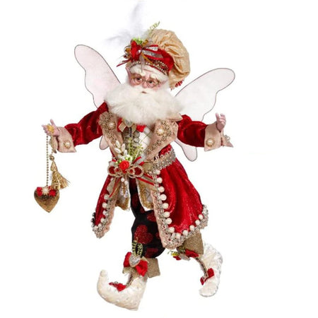 Fairy figure holding a red heart hanging from a chain. He wears red bloomer type pants and a long red jacket with embellishments.  Matching white booties and a chef style hat. White wings.