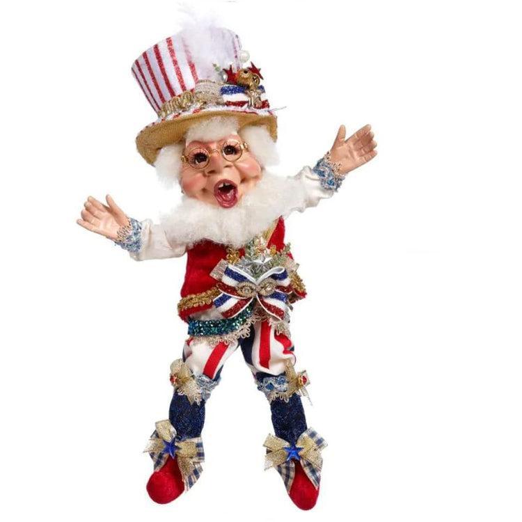 Elf figure wearing a red, white and blue outfit.  Bloomer pants, booties and a top hat all in red white and blue with stripes and a solid red vest.  Hat is top hat style.