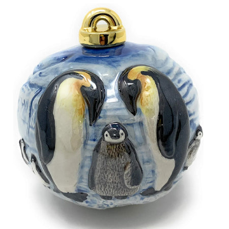 porcelain ball shaped ornament with three dimensional penguins with a baby penguin.