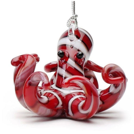 Red glass octopus ornament with white black outlined stripes. Eyes on head with tentacles all curled up. Hanger on top.