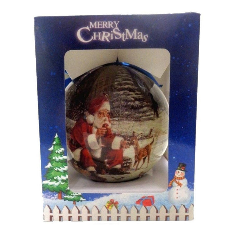Round ball ornament sits inside open front box. Box has text "Merry Christmas" Ball shows Santa feeding deer & raccoon