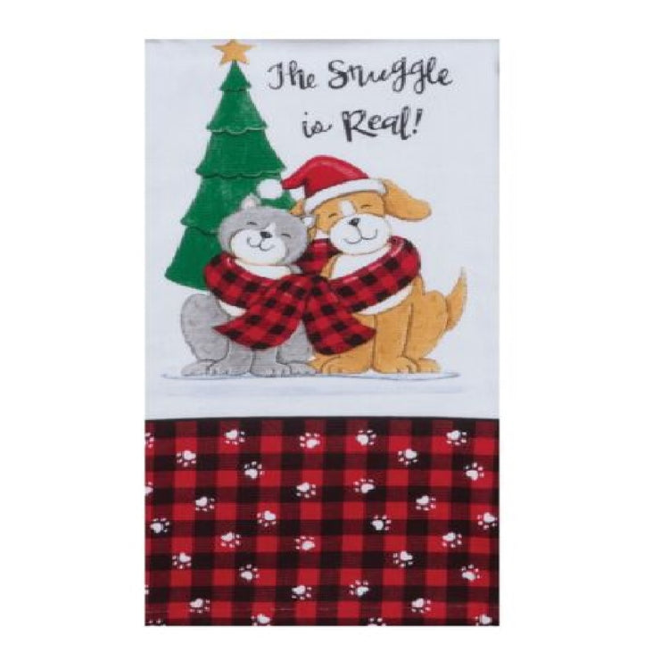 white towel with printed design of a pine tree, a grey cat and yellow puppy sharing a red and black plaid scarf. "The struggle is real!" is printed above them, and a red and black plaid border accented with white paw prints along the bottom of the towel.