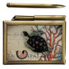 Bronze note pad case with glass picture of a sea turtle and coral. Pen shown out of holder.