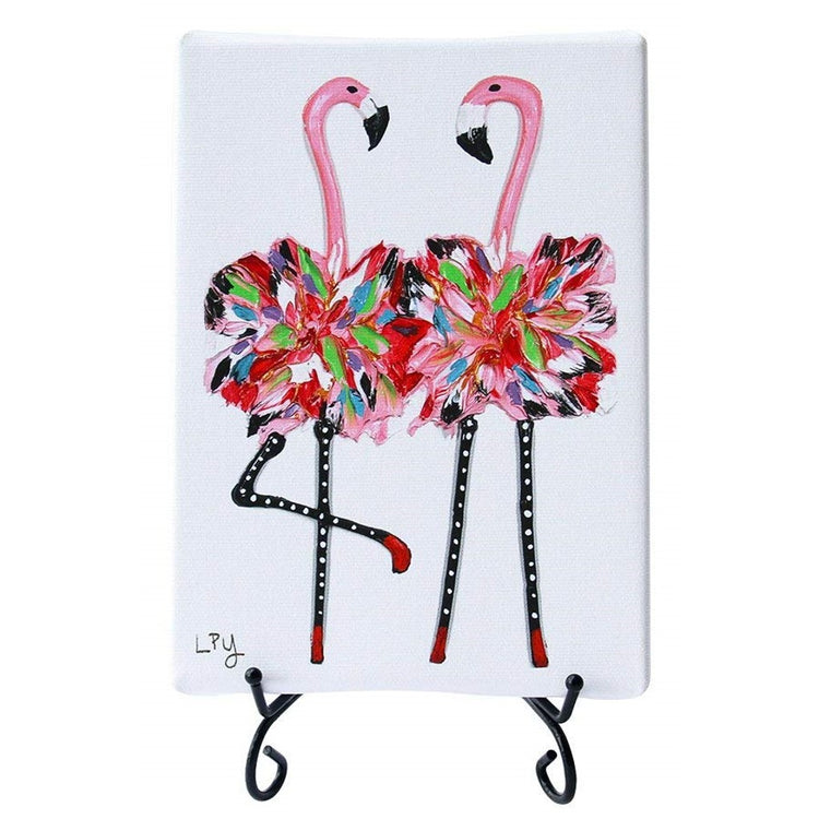 White canvas rectangle on black wire stand with 2 pink flamingos wearing colorful tutu's.