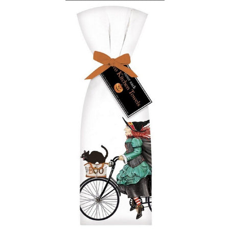 2 white towels tied with orange ribbon. Towel shows a witch riding a black bike with a black cat in the basket.
